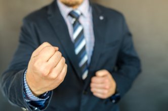 Guy in a suit with clenched fists like he's going to throw a punch.