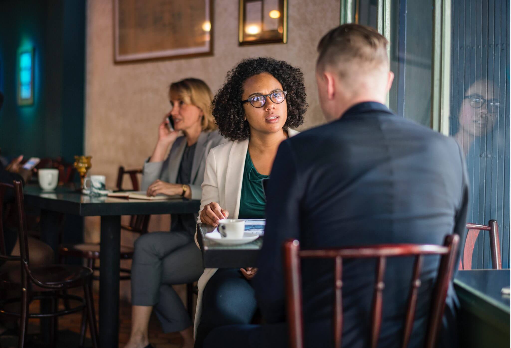 Two colleagues sitting in a restaurant. One with a displeased look on her face.