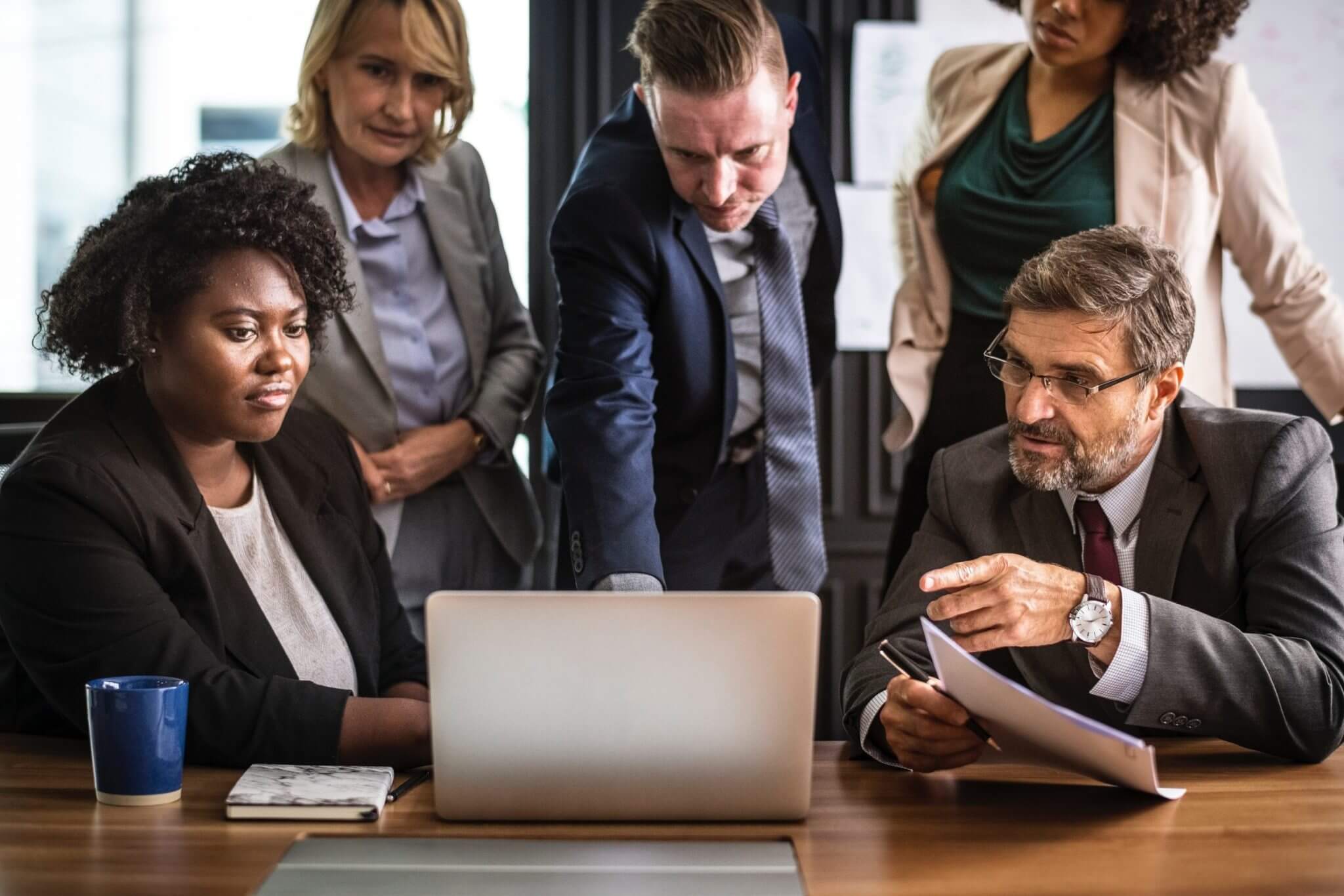 Group of people sitting around a laptop discussing something. Group of people sitting around a laptop discussing something.