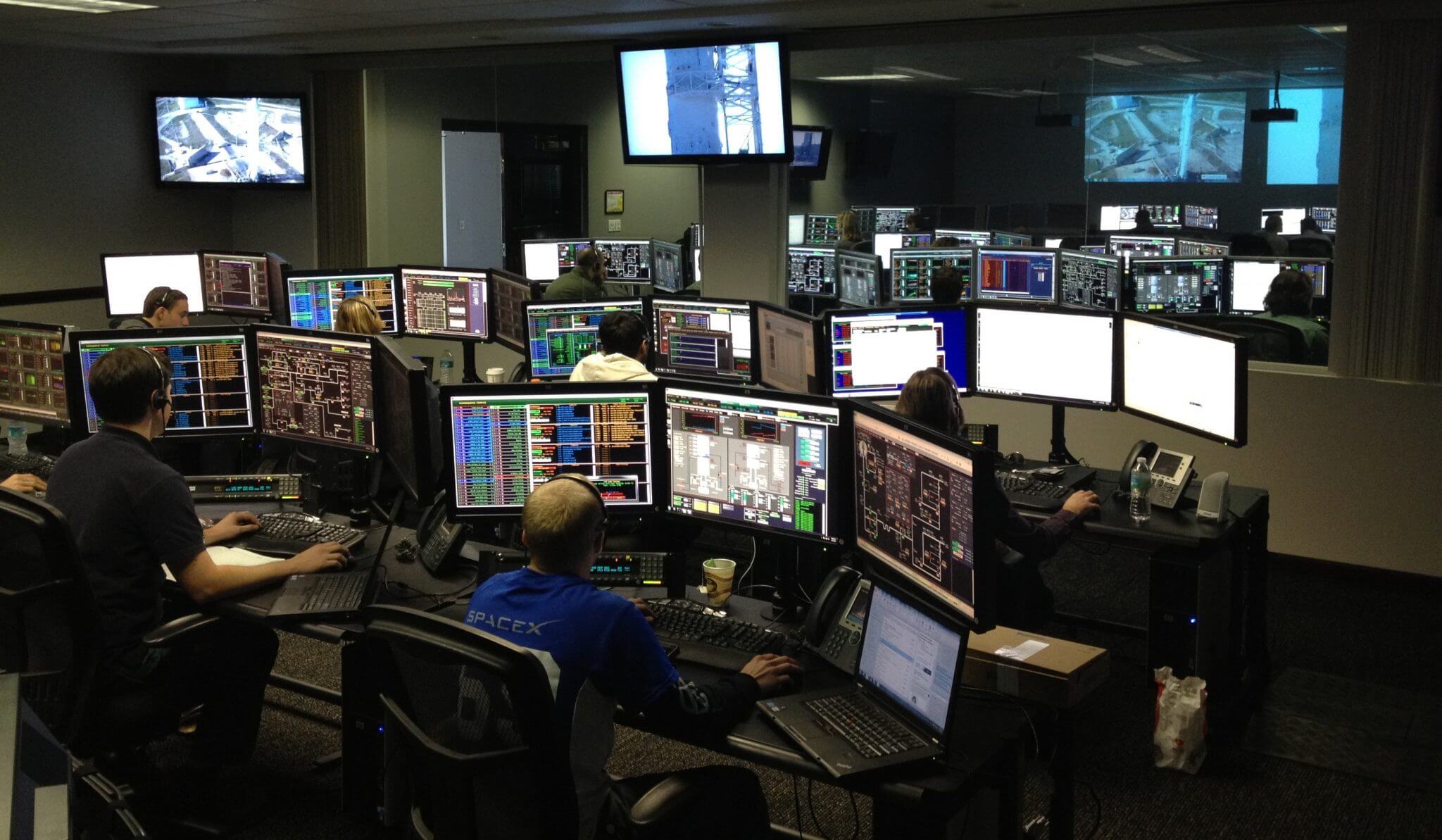 Dark room of computer screens. Looks like a hub for security or IT.