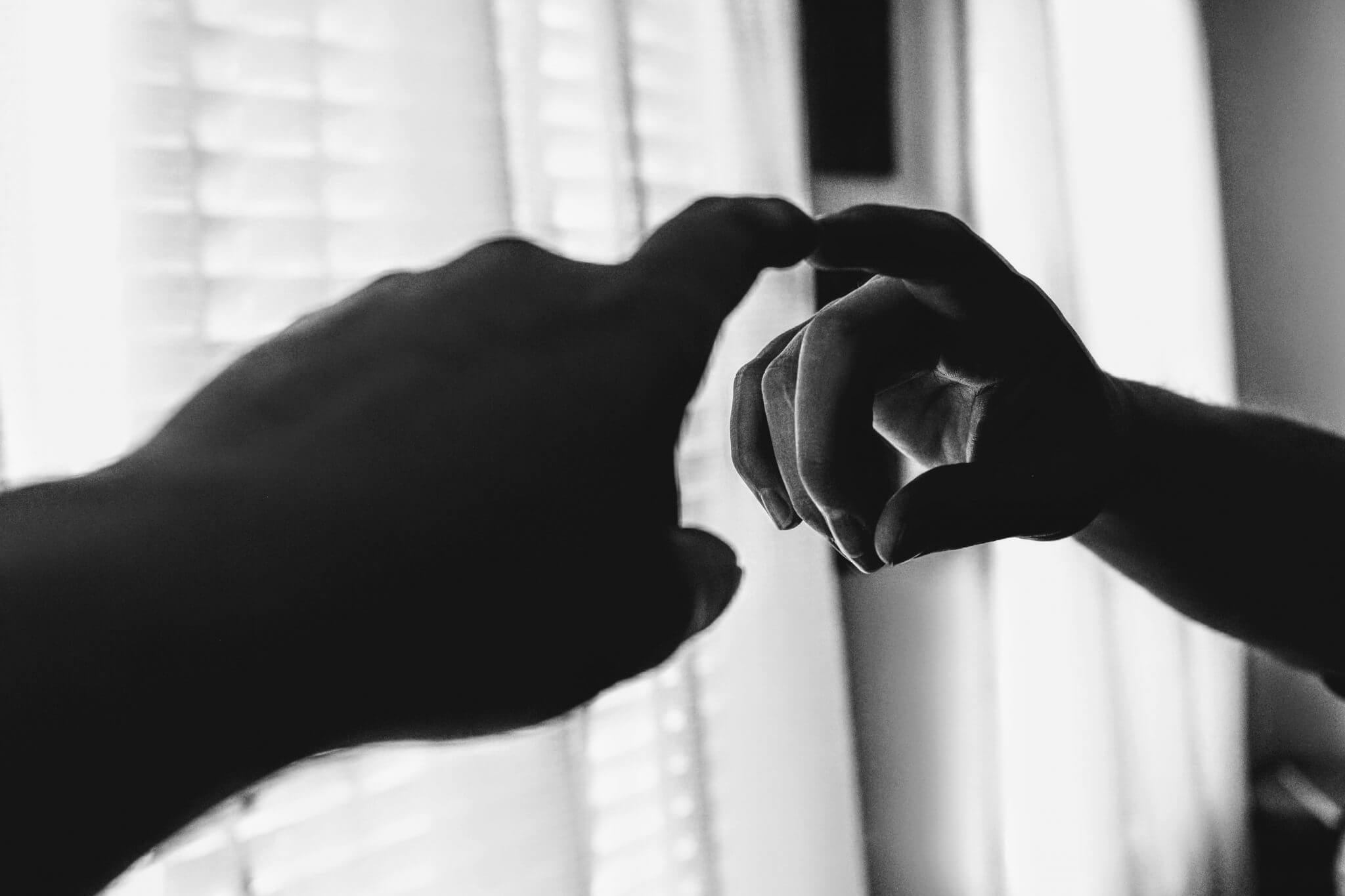 Black and white image of finger pointing at itself in the mirror.