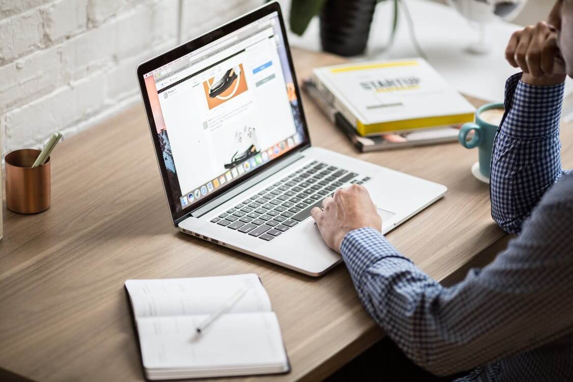 Employee writing a job ad sitting at a desk near a computer.