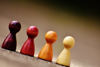 Small wooden figurines of different colors resembling people lined up next to each other