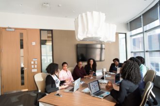 Group of employees sitting around a desk in a conference room having a discussion.