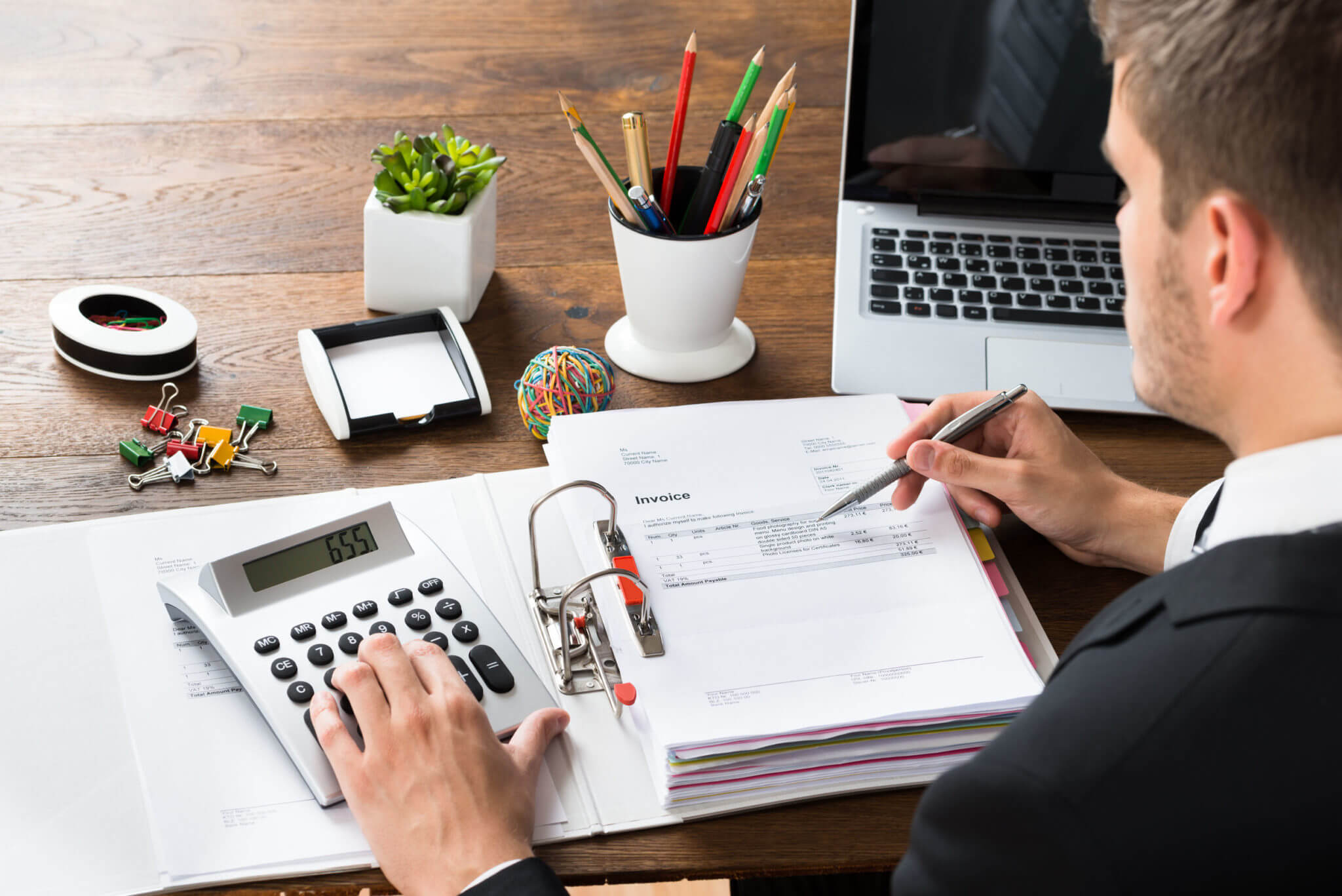 close-up of businessman calculating receipt with calculator at desk