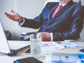 Guy in suit sitting at his desk on a video conference call.