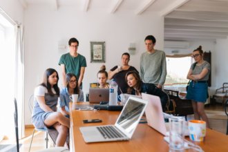 adults sitting around a table and laptop brainstorming ideas