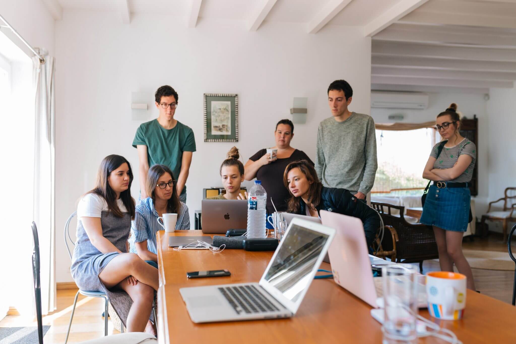 adults sitting around a table and laptop brainstorming ideas