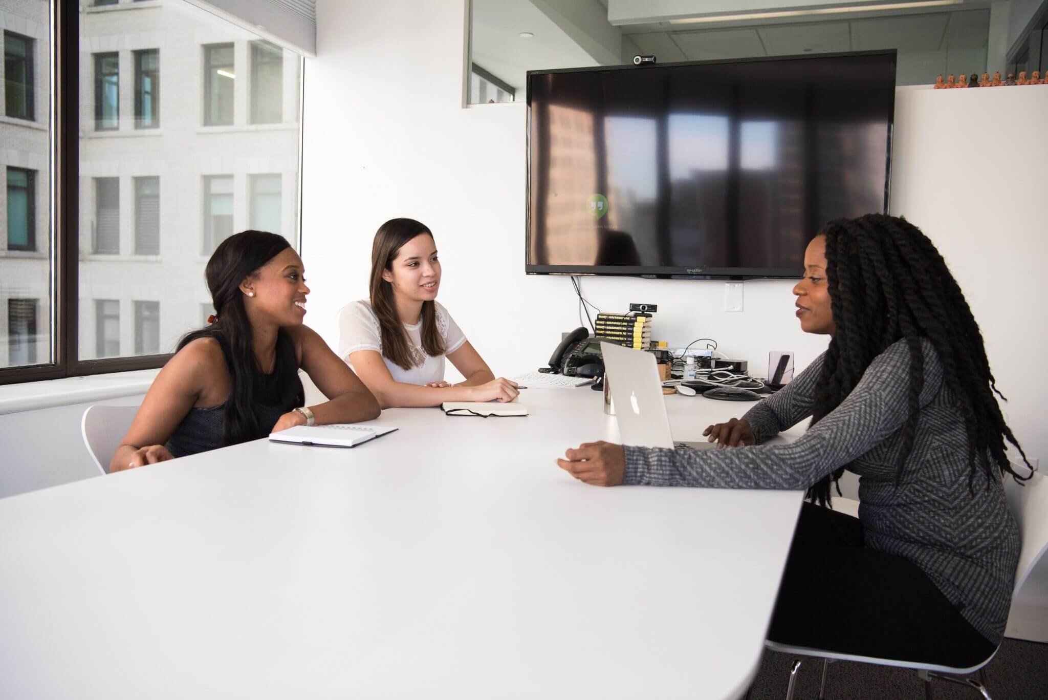 Business women sitting at a conference table having a discussion.