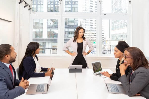 Leader of a company standing in front of a conference table with seated employees