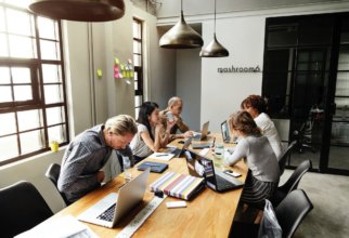 Employees huddled around a desk collaborating on a project.