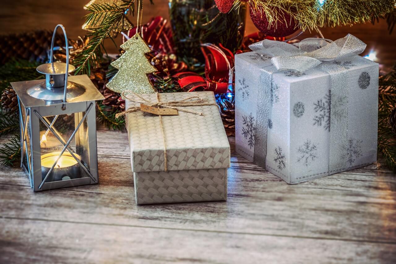 Close up shot of Christmas gifts sitting on the floor near a tree