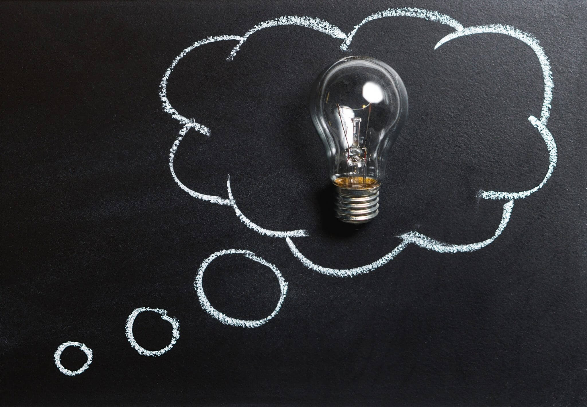 light bulb within a thought bubble on a chalkboard signifying an idea or something clever.