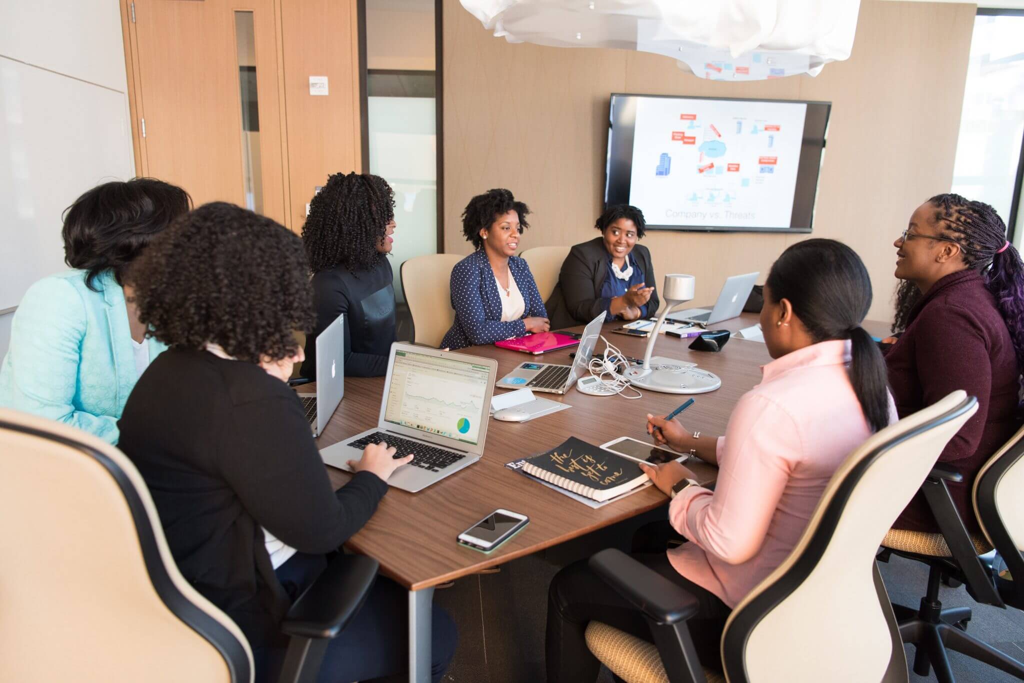 Team of employees sitting around a table in a meeting having a discussion.