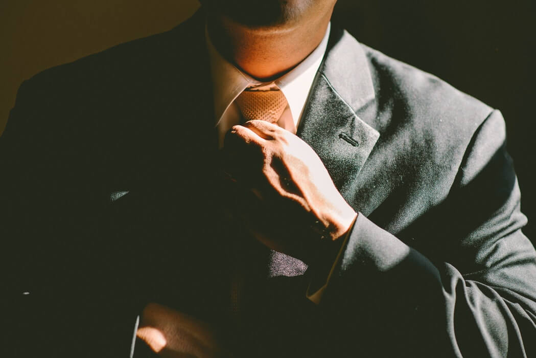Man in a suit straightening his tie