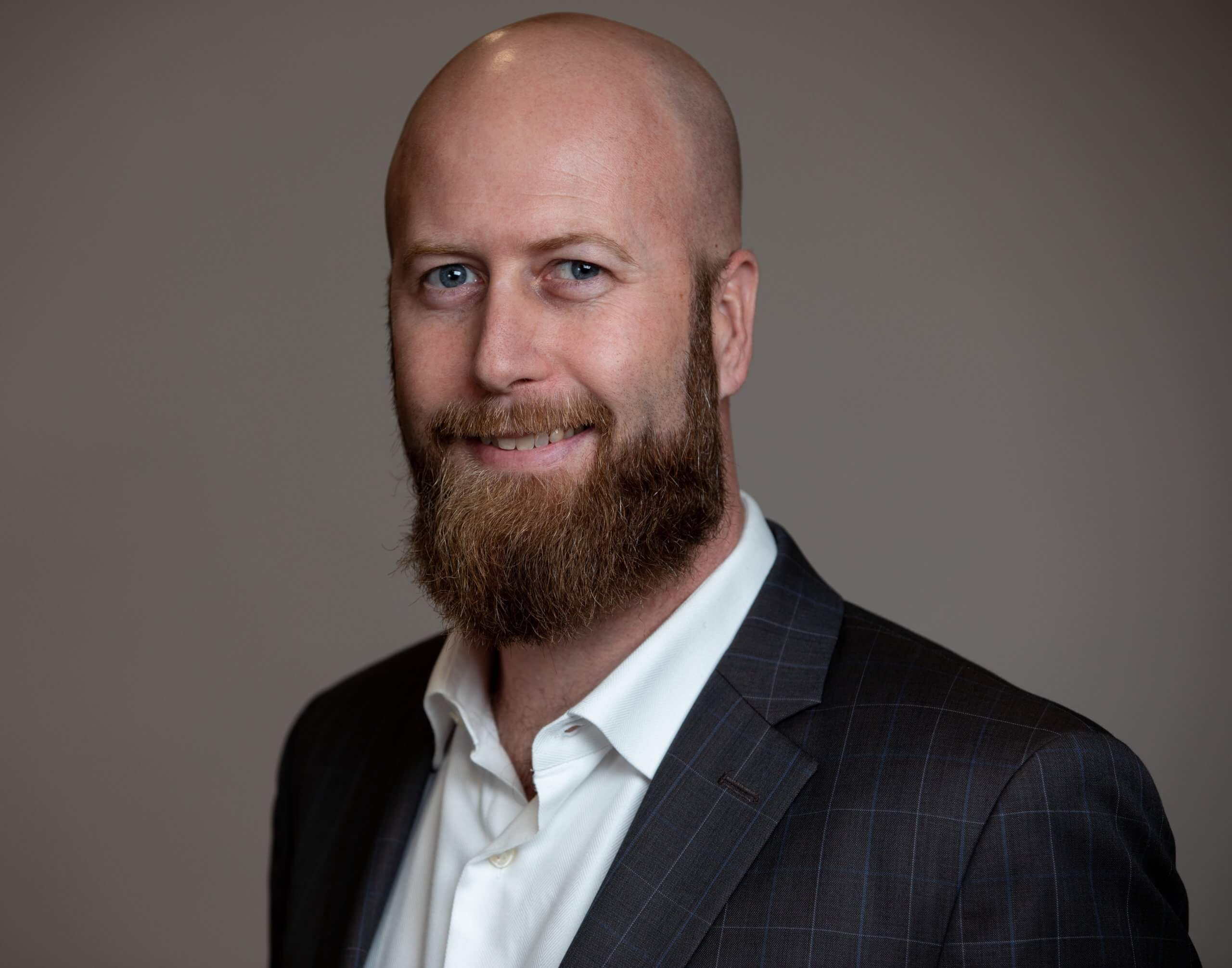 A bald man wearing a suit and a white shirt.