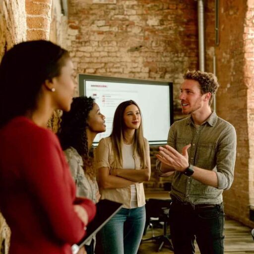 A leader presenting to engaged professionals in a modern office, symbolizing the importance of leadership assessment as the cornerstone of success.