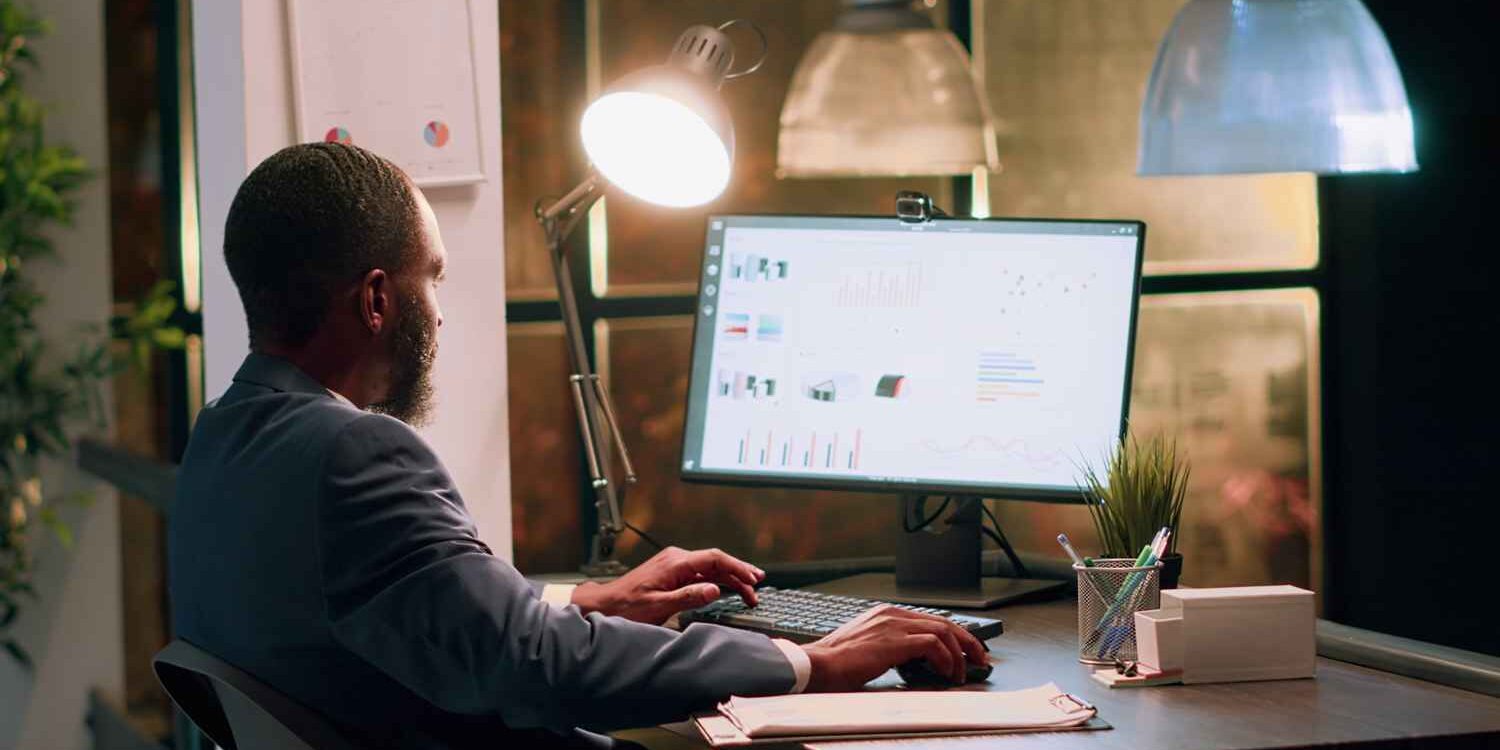 Professional man analyzing performance dashboards on a desktop screen, reviewing business intelligence from employee assessments and analytical tests.