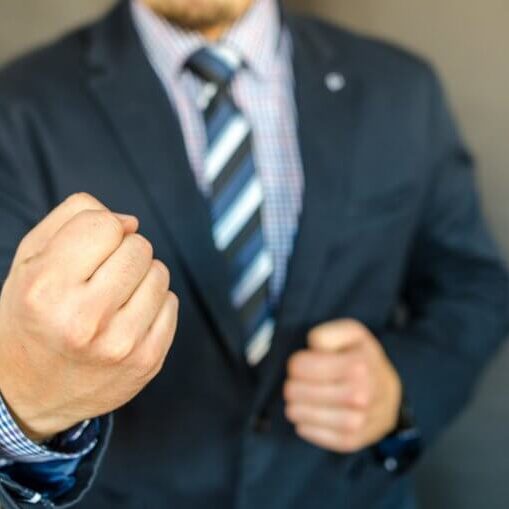 Guy in a suit with clenched fists like he's going to throw a punch.