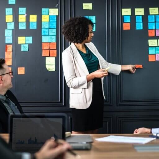 Employee in front of a team, sharing ideas and presenting on sticky notes