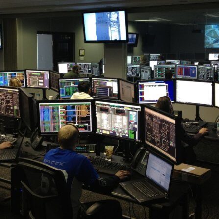 Dark room of computer screens. Looks like a hub for security or IT.