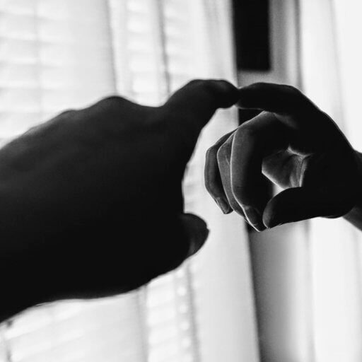 Black and white image of finger pointing at itself in the mirror.