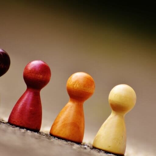 Small wooden figurines of different colors resembling people lined up next to each other