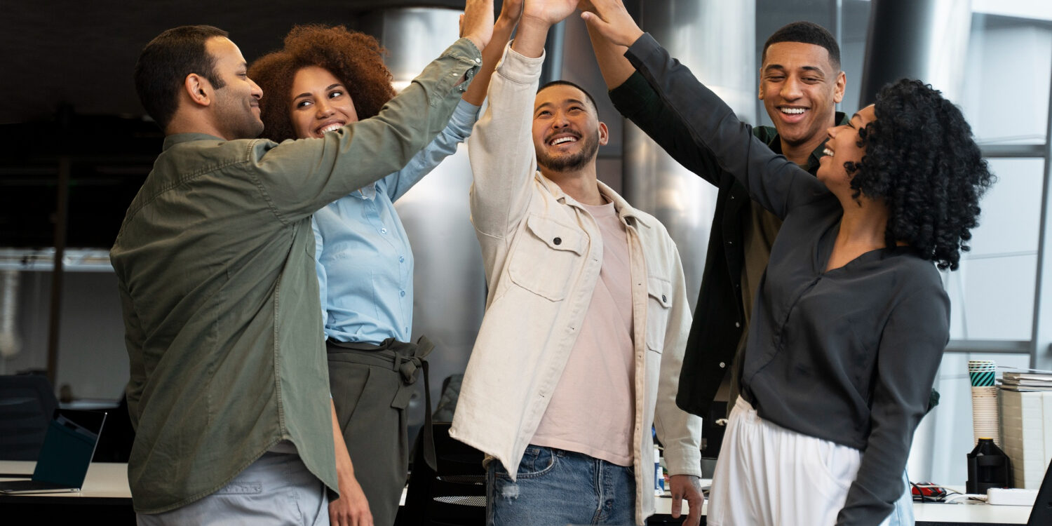 Diverse team celebrating success at the workplace, reflecting positive outcomes of personality and behaviour-based assessment tests for team building.
