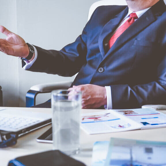 Guy in suit sitting at his desk on a video conference call.