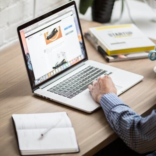 Employee writing a job ad sitting at a desk near a computer.