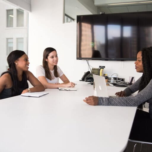 Business women sitting at a conference table having a discussion.