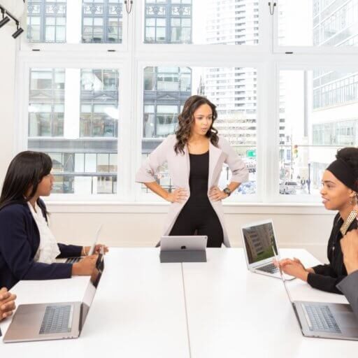 Leader of a company standing in front of a conference table with seated employees