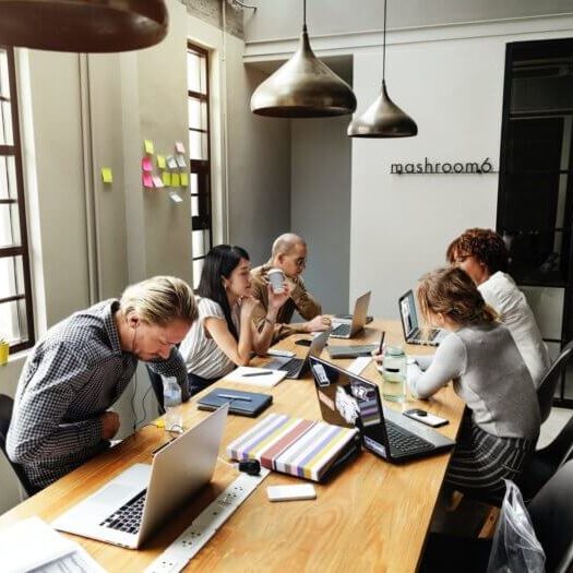 Employees huddled around a desk collaborating on a project.