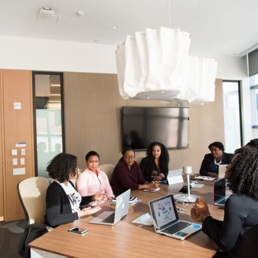 Group of employees sitting around a desk in a conference room having a discussion.