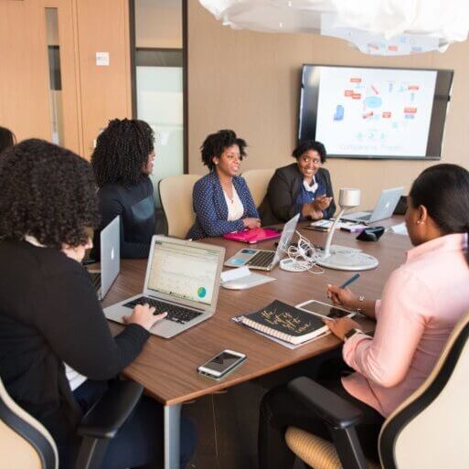 Team of employees sitting around a table in a meeting having a discussion.
